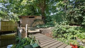 un jardín con una pasarela de madera y un edificio de madera en Studio in Woonboot + privébadkamer en -tuinterras, en Utrecht