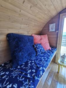 Cama en una casa pequeña con sábanas azules y almohadas rosas en Manija saare süda - Manija island, en Pärnu