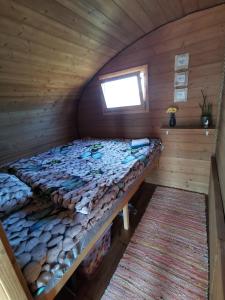 a bed in a wooden cabin with a window at Manija saare süda - Manija island in Pärnu