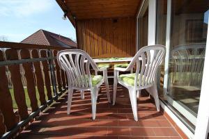 2 chaises assises sur la terrasse couverte d'une maison dans l'établissement Ferienwohnung Ahrens im Salzmoor, à Müden
