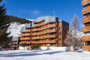 un bâtiment dans la neige devant une montagne dans l'établissement Vacancéole - Résidence Plein Sud, à Les Deux Alpes