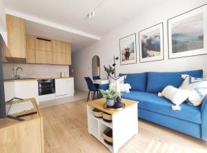 a living room with a blue couch and a kitchen at Mogilska 120D by Homeprime in Kraków