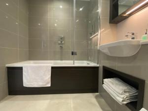 ein Badezimmer mit einer Dusche, einer Badewanne und einem Waschbecken in der Unterkunft Club White London Bridge One Bedroom Apartment in London