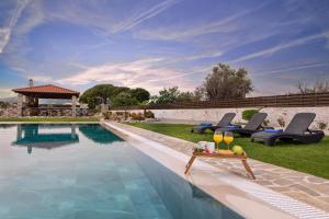 una piscina con due sedie e un tavolo accanto ad essa di Marble Pool Villa a Pastida