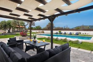 a patio with a table and chairs and a pool at Marble Pool Villa in Pastida