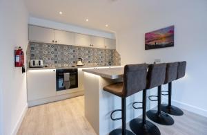 a kitchen with a counter and two bar stools at Mrs Watermelon Apartment in Fort William