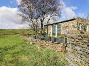 a stone house with a stone wall at The Barn at Crow Hill Shaw Farm in Sowerby Bridge