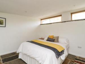 a bedroom with a bed with white walls and two windows at The Barn at Crow Hill Shaw Farm in Sowerby Bridge