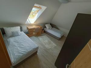 a small attic bedroom with two beds and a window at Flower Apartman 6 