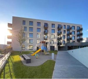 um edifício de apartamentos com um parque infantil em frente em Po City Newly Built Apartment em Presov