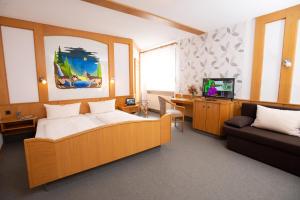 1 dormitorio con cama, sofá y TV en Landhotel zum Stern en Waldkappel
