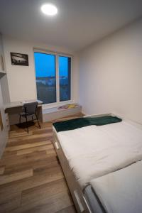 a bedroom with a bed and a desk and a window at Po City Newly Built Apartment in Prešov