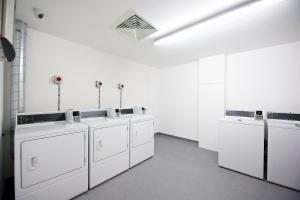 a white laundry room with white washers and sinks at Staycity Aparthotels London Greenwich High Road in London