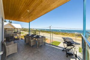 a balcony with a table and chairs and a view of the ocean at Ocean Sunset - Luxury Apartment with Ocean Views in Lancelin
