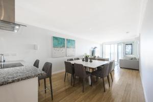 uma cozinha branca e sala de jantar com mesa e cadeiras em Oceans Waves - Luxury Apartment with ocean views em Lancelin