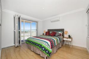 um quarto com uma cama e uma grande janela em Oceans Waves - Luxury Apartment with ocean views em Lancelin