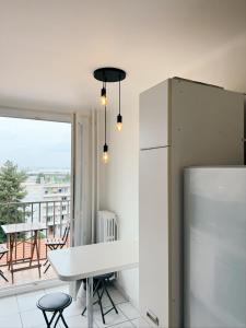 uma cozinha com um frigorífico, uma mesa e uma varanda em APPARTEMENT SPACIEUX AVEC BALCON em Saint-Fons