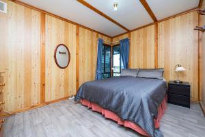 ein Schlafzimmer mit einem Bett in einem Zimmer mit Holzwänden in der Unterkunft Sea Breeze - Perfect house for the family in Lancelin