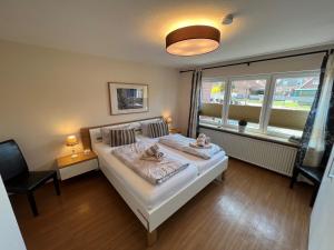 a bedroom with a bed and a chair and a window at Steerenklipp Kieker Bungalow 2 in Borkum