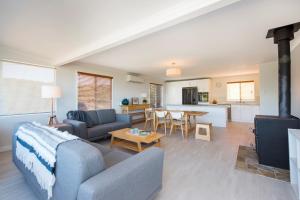 a living room with a couch and a table at Seaclusion Cottage - Modern renovated beach house in Guilderton