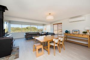 a living room with a table and a couch at Seaclusion Cottage - Modern renovated beach house in Guilderton