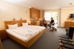1 dormitorio con 1 cama, 1 mujer y 1 perro en Landhotel zum Stern, en Waldkappel
