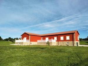 un bâtiment rouge dans un champ avec un champ vert dans l'établissement Alojamiento Cabarceno, à Agüero