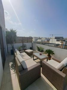 a balcony with couches and tables on a roof at the Queen Freddy Penthouse in Taʼ Xbiex