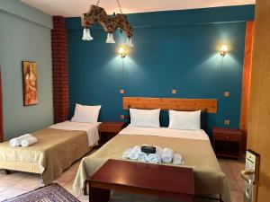two beds in a room with blue walls at Margaret's Island Hotel in Naousa