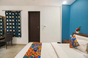 1 dormitorio con cama y pared azul en FabHotel Usha Continental, en Muthiganj