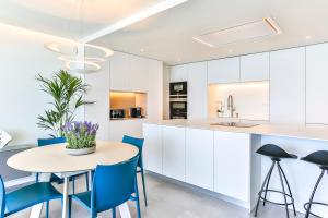 a kitchen with white cabinets and a table with blue chairs at MAGNÍFICO APARTAMENTO - primera línea de mar in Calafell