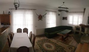 a living room with a table and a green couch at Șoaptele pădurii & Căsuța din pădure in Suceviţa +23 photos