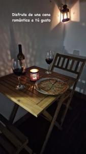 a wooden table with a pizza and two glasses of wine at Apartamento Punta Umbría junto a la Ría in Punta Umbría