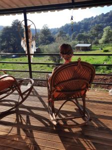 una mujer sentada en una silla en un porche mirando al campo en Field Of Possibilites - Kayakoy Retreat en Kayakoy