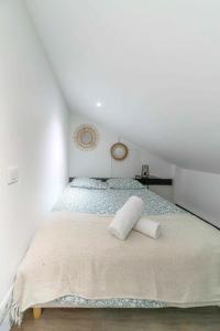 een witte slaapkamer met een bed op zolder bij Résidence Le Celest - Appartements climatisés - Centre ville in Vichy