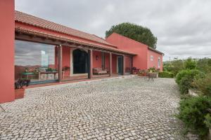 ein rotes Haus mit einer Steinterrasse in der Unterkunft Luxury Farmhouse with Swimming Pool, By TimeCooler in Sobral de Monte Agraço