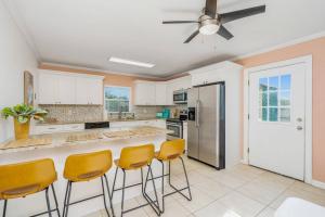 a kitchen with white cabinets and yellow bar stools at Crescent Beach Bungalow B in Saint Augustine
