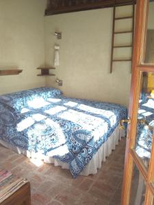 a bedroom with a bed with a blue and white blanket at Casita de Piedra B&B in Villa del Dique