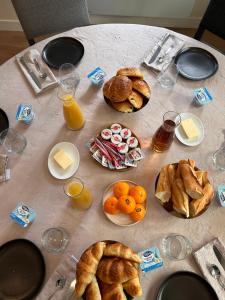 una mesa con un montón de alimentos para el desayuno y zumo de naranja en Auberge de la rose, en Anet