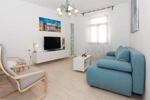 ein Wohnzimmer mit einem blauen Sofa und einem TV in der Unterkunft Casa della Fortuna by Locap Group in Piran