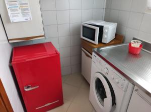 una piccola cucina con frigorifero rosso e forno a microonde di L'anfiteatro a Vercelli