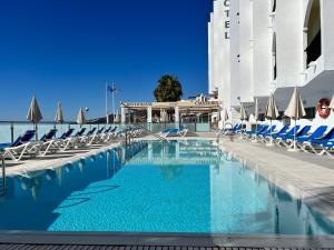 a swimming pool with chairs and a building at Perla Marina in Nerja