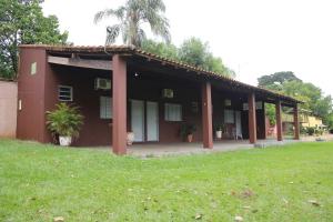 a red building with a grass field in front of it at Espaço Colibri in Ribeirão Preto