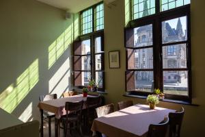 a restaurant with tables and chairs and windows at Hostel Uppelink in Ghent