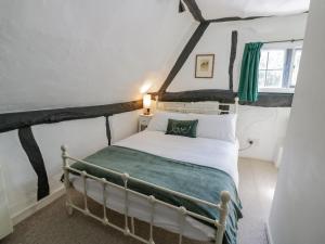 a bedroom with a white bed with a green blanket at Bluebell Cottage in Stratford-upon-Avon