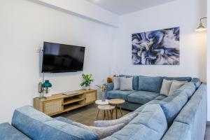 a living room with a blue couch and a tv at Servani Apartment in Skopelos Town