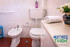 a white bathroom with a toilet and a sink at Casa do Mirante in Praia da Vitória