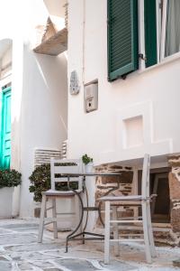 two chairs and a table in front of a building at Aggelikoula Rooms in Tinos Town