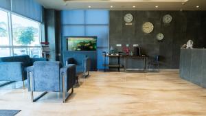 a waiting room with blue chairs and clocks on the wall at 7 Apple Hotel Aurangabad in Aurangabad +43 photos