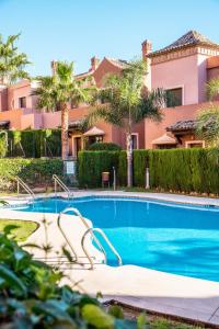 a swimming pool in front of a house with palm trees at Townhouse Azata Golf in Estepona